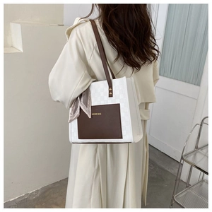 Détail du sac cabas contrasté avec motif en damier et foulard en soie sur la poignée