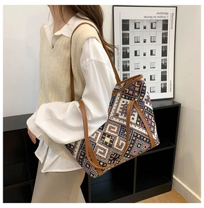 Detail of colorful geometric woven pattern and brown faux leather strap on large tote bag