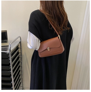 Brown vintage saddle bag with gold buckle shown on shoulder for size reference