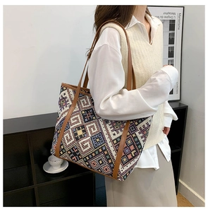 Close-up of geometric woven pattern and brown leather straps on large canvas tote bag