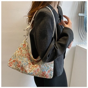 Detail of vintage canvas hobo bag with floral patterns and braided rope shoulder strap