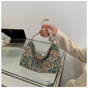 Detail of vintage floral jacquard fabric with soft beige knotted handles on shoulder bag