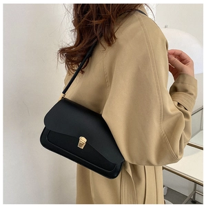 Close-up of matte black leather saddle bag featuring a stylish gold metal clasp closure
