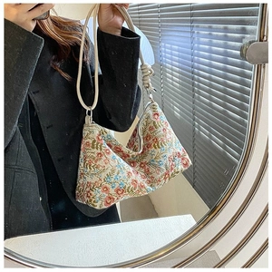 Close-up of vintage floral canvas shoulder bag with woven rope handle and metal rings