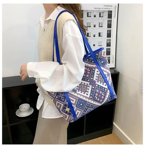 Detail of multi-color woven canvas tote bag with royal blue faux leather straps