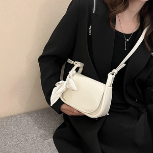 Mini off-white crossbody bag with silk scarf detail worn by model in black blazer