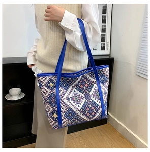 Detail of colorful geometric ethnic pattern canvas tote with bright blue leather handles