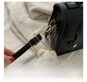 Close-up of golden metal hooks and black leather strap with a cute plush bear charm