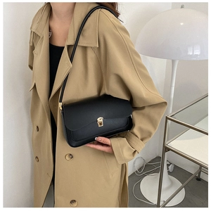 Detail of black matte leather saddle bag featuring a gold square buckle and shoulder strap