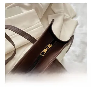 Detail of premium gold metal zipper and stitching on a dark brown leather tote bag
