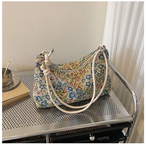Detail of floral tapestry fabric and knotted rope strap on a vintage underarm bag