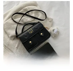 Detail view of mini black PU leather flap bag with gold bear logo and phone size comparison