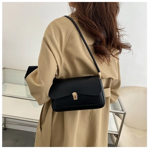Close-up of black leather saddle bag featuring a stylish gold square metal buckle detail
