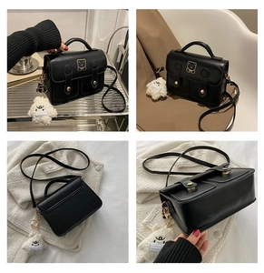 Detail view of black vintage crossbody bag with gold bear buckle and plush charm