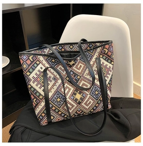 Close-up of geometric woven tote bag with colorful tribal patterns and black leather handles