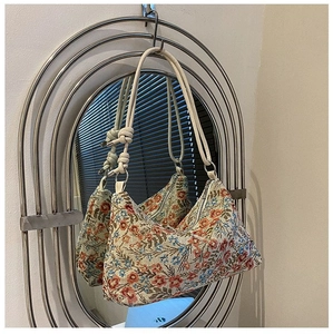Detail of floral tapestry hobo bag reflected in a vintage mirror with knot strap