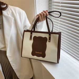 Detail of contrast stitching tote bag with Guihuashi logo and elegant brown strap handle