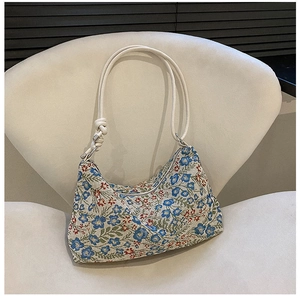 Detailed close-up of floral embroidery texture and rope strap on the hobo handbag