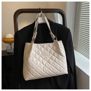 Détail du sac cabas matelassé beige à motif de losanges sur un cintre avec un blazer