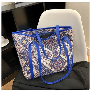 Detailed macro view of geometric woven fabric and blue leather handle on a large tote bag