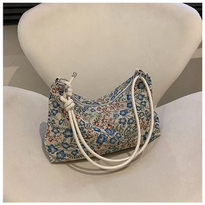 Detail of floral jacquard hobo bag with red and blue embroidery on a white chair