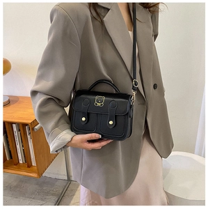 Detail of a black crossbody bag featuring a golden bear logo and adjustable shoulder strap