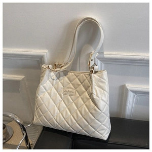 Détail du sac cabas matelassé blanc avec broderie fine et accents métalliques dorés