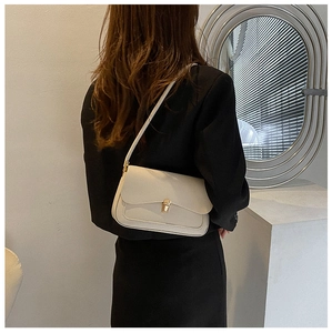 Detailed view of cream saddle bag with golden square metal twist lock and fine stitching