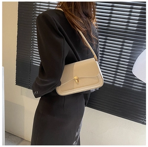 Detail of beige leather baguette bag with gold metal buckle on black blazer