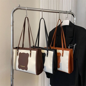 Three minimalist tote bags in brown, black, and orange with wave-edge contrast design