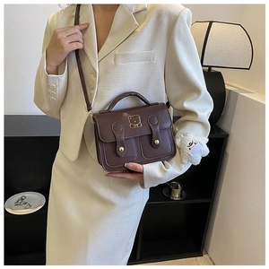 Brown vintage faux leather handbag featuring a golden bear logo and plush charm detail