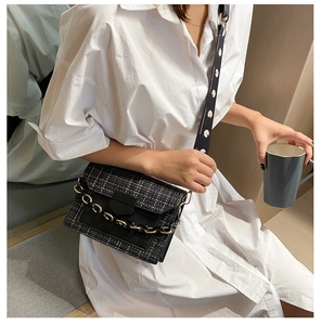 Detail of tweed crossbody bag featuring a metal chain and daisy floral wide strap