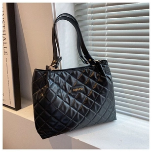 Détail d'un sac cabas noir matelassé avec motif losanges sur un rebord de fenêtre