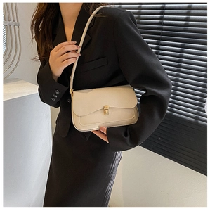 Detailed side view of the cream white vintage saddle bag on a model in a black suit