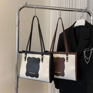 Close-up of minimalist contrast tote bags with logo detail hanging on a metal rack