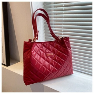 Détail du sac cabas matelassé rouge avec texture en losanges et plaque de logo carrée
