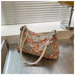 Close-up of floral jacquard fabric and rope strap details on a vintage hobo bag