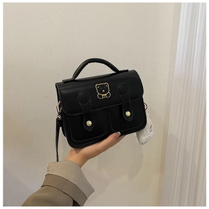 Detail of vintage black leather handbag featuring golden bear motif and double front pockets