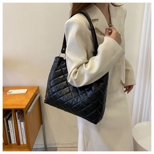Grand sac cabas noir matelassé en cuir PU avec anneaux dorés porté par un mannequin