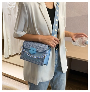 Detail of light blue tweed crossbody bag with chunky chain and daisy print wide strap