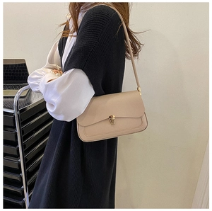 Close-up of cream saddle bag featuring a gold metal twist lock and fine stitching detail