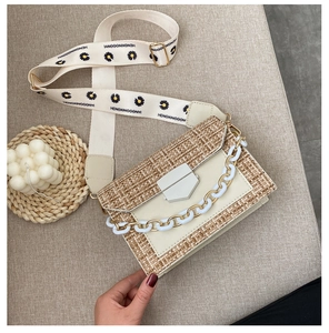 Detail of woven crossbody bag featuring daisy print wide strap and white chain link