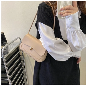 Detail of minimalist apricot saddle bag with elegant gold metal buckle and smooth flap