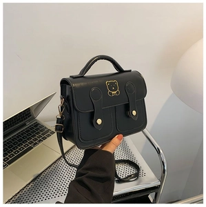 Detail of black crossbody bag with gold bear graphic and adjustable shoulder strap