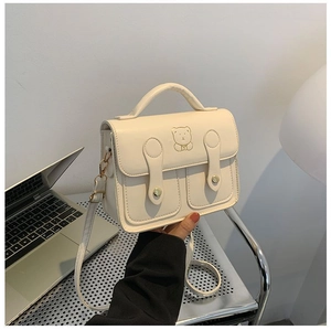 Close-up of cream PU leather small square bag featuring cute bear embroidery and dual buckles