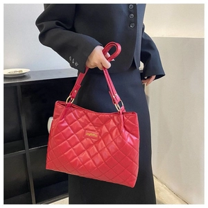 Gros plan sur un grand sac cabas rouge matelassé avec surpiqûres diamant et détails dorés
