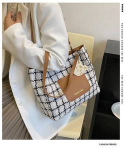 Détail du sac cabas en tweed à carreaux avec poche en cuir et breloque chat blanc