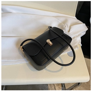 Detail view of a black minimalist saddle bag with a golden rectangular twist lock and strap