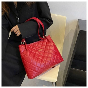 Détail du sac cabas matelassé rouge avec plaque logo métallique et finition brillante