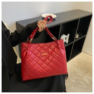 Gros plan du sac cabas matelassé rouge avec finition brillante et détails dorés